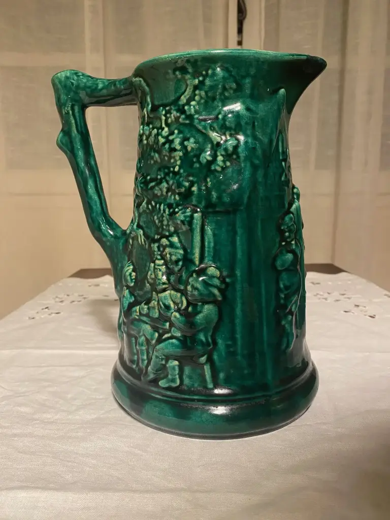 Cruche en barbotine signée Sarreguemines, superbe carafe verte et intérieur bleu, au décors de personnages, XIXème siècle. Juste un petit choc au bec.                           Barbotine jug signed Sarreguemines, superb green carafe and blue interior, with character decorations, 19th century. Just a small shock to the spout.