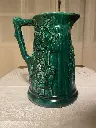 Cruche en barbotine signée Sarreguemines, superbe carafe verte et intérieur bleu, au décors de personnages, XIXème siècle. Juste un petit choc au bec.                           Barbotine jug signed Sarreguemines, superb green carafe and blue interior, with character decorations, 19th century. Just a small shock to the spout.