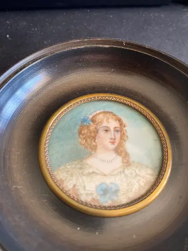 Jolie miniature ancienne signée, forme médaillon et cadre en bois noirci, au contour en bronze. En bel état et finement peint. De la maison "Merveille de France", monogrammé au dos.